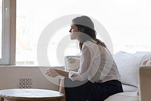 Woman sit on sofa thinks over relationships end looks unhappy