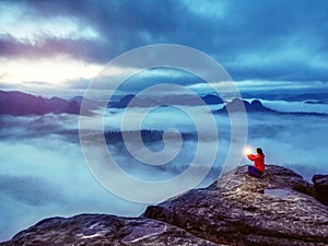 Woman sit on summit in hands holding flash bolb. Girl waiting