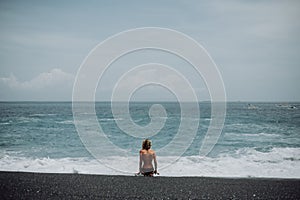 Woman sit on tropical beach black sand nacked