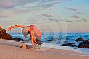 Woman sit in yoga pose on sunset sea beach