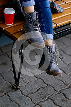 Woman siting on bench in gray boots