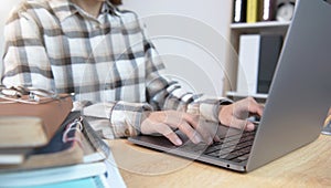 Woman siting on desktop and hands typing on computer laptop keyboard at home office