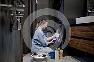 Woman siting in front of a washing machine loading dirty clothes, napkins for washing colored clothes