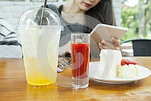 Woman siting on wood table with smart pad in hand and strawbery crape cake ready to eat on table