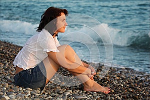 Woman sits ashore of sea photo