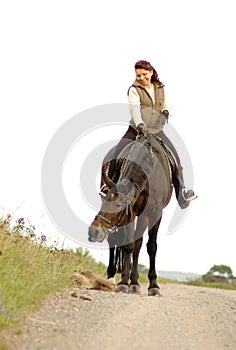 Woman sits astride a horse on white background.