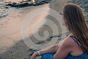 Woman sits on the beach and looks at the sea in Alanya city