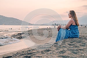 Woman sits on the beach and looks at the sea in Alanya city