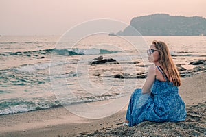 Woman sits on the beach and looks at the sea in Alanya city