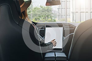 Woman sits behind wheel in car and uses electronic dashboard. Girl traveler looking for way through navigation system.