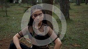 A woman sits bravely with black dresses and long black hair in the jungle