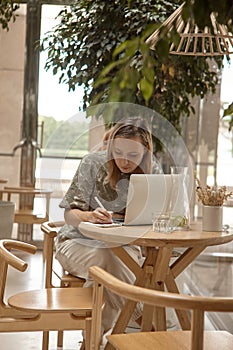 A woman sits in a cafe and work at a laptop