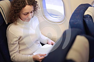 Woman sits in chair near illuminator of airplane photo