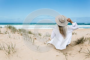 Woman sits on a clean sandy beach in Australia