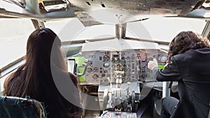 A woman sits in the cockpit of an airplane with a man next to her