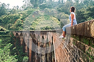 Woman sits on the Demodara nine arches bridge the most visited s