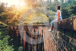 Woman sits on the Demodara nine arches bridge the most visited s