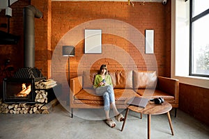 Woman sits with gadgets in modern living room in loft style at home