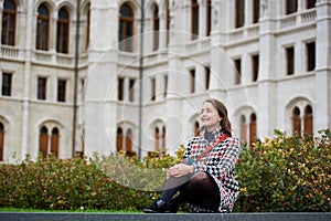 Woman sits on grass at background of Palace Parliament, Budapest