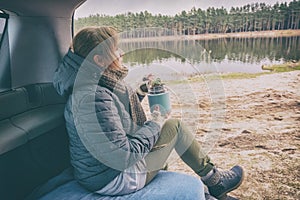 Woman sits in her car and eating a warm meal from a thermos