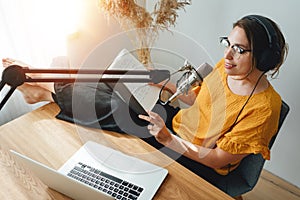 Woman sits with his feet up on his desk and recording live podcast