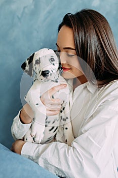 Woman sits and hugs puppy of dalmatian dog