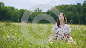 Woman sits in lotus pose meditating outdoors, wind moves hair, oneness nature
