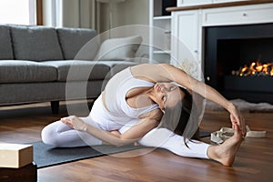 Woman sits on mat in living room perform yoga asanas