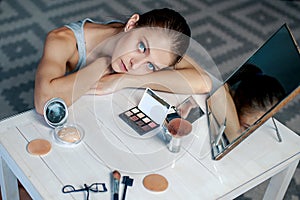 Woman sits before mirror. Woman making make-up