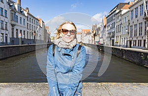 Woman sits near water on Jan van Eyck Square in Bruges, Belgium