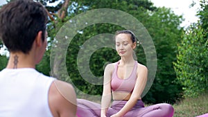 Woman sits opposite man meditating in Lotus pose smiling