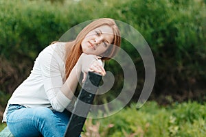 A woman sits in a park on a bench and is sad on a spring evening