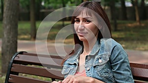 A woman sits on a park bench. Slide movie