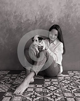 Woman sits and plays with puppy of dalmatian dog