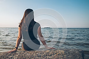 Woman sits on the rock and lookin for lake view