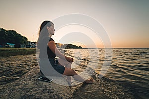 Woman sits on the rock and lookin for lake view