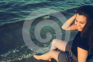 Woman sits on the rock and lookin for lake view