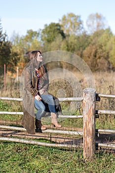 Woman sits on a rural fence