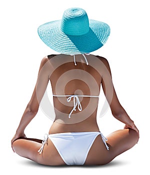 A woman sits seen from behind, she wears a bikini and a sun hat, isolated on white background concept of hot summer beach holiday