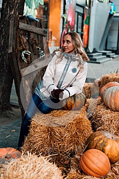 A woman sits on straw with pumpkins. Ingathering. Halloween Celebration