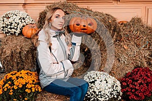 A woman sits on straw with pumpkins. Ingathering. Halloween Celebration