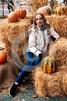 A woman sits on straw with pumpkins. Ingathering. Halloween Celebration