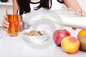 Woman sits at a table and eat breakfast. Women eating healthy food for breakfast. Fruit, cereal and milk, close up selective focus