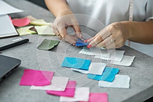 Woman sits at table in modern office next to color palette and fabric samples for design project