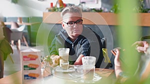 A woman sits at a table in a restaurant with an interlocutor.