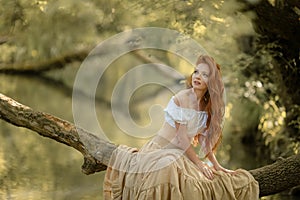 A woman sits on a tree branch lowered over the river