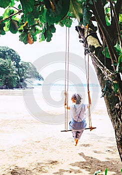 Woman sits on the tree swing on the Weligama sandy beach coast