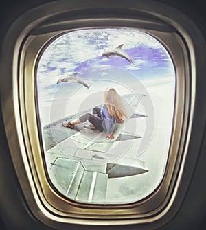 Woman sitting on airliner wing and looks at dolphins