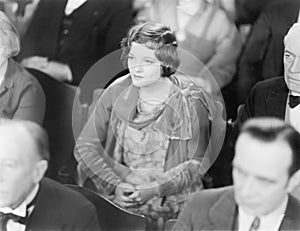 Woman sitting in a auditorium listening with folded hands