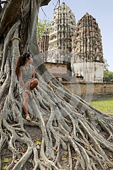 Woman sitting banyan roots tree sukhothai Thailand